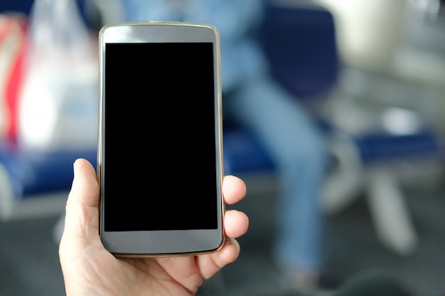 Foto mano que sostiene el teléfono inteligente móvil en el aeropuerto