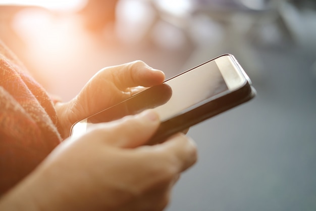 Mano que sostiene el teléfono inteligente móvil en el aeropuerto