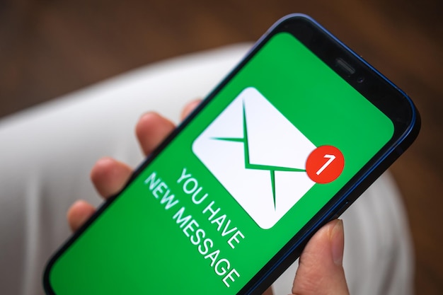 Foto mano que sostiene el teléfono inteligente con el nuevo concepto de mensaje en la pantalla nueva foto de fondo comercial de notificación por correo electrónico