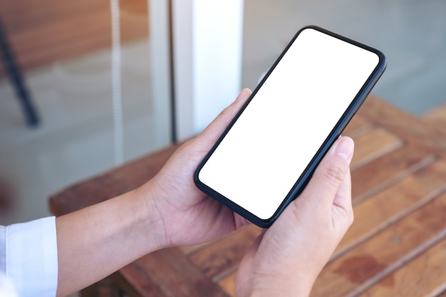 mano que sostiene el teléfono móvil negro con pantalla de escritorio en blanco