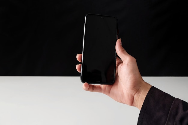 Una mano que sostiene un teléfono negro con una pantalla negra