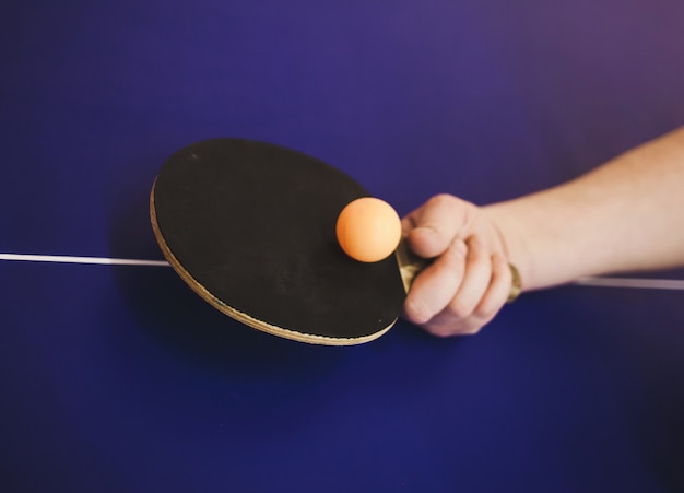 Mano raquetas de tenis de mesa en mesa azul