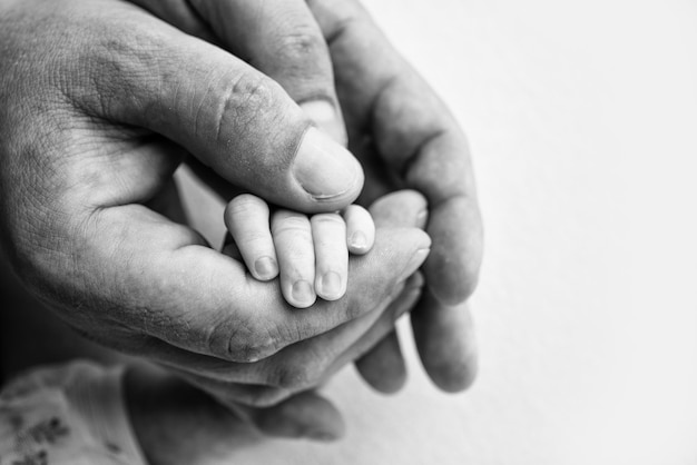 La mano de un recién nacido dormido en la mano de los padres madre y padre primer plano Dedos diminutos de un recién nacido La familia se toma de la mano Fotografía macro en blanco y negro Conceptos de familia y amor