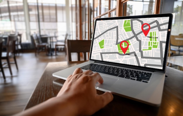 Mano recortada buscando GPS en la computadora portátil en el café