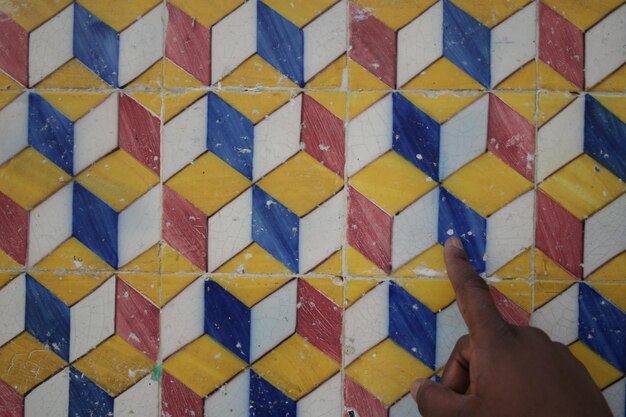 Foto la mano recortada en el colorido suelo de azulejos