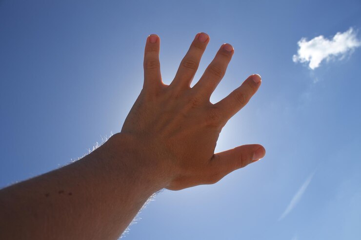 Foto mano recortada contra el cielo azul