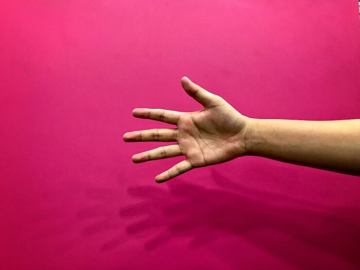 Foto mano recortada contra un fondo rosado
