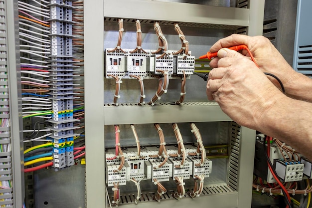 Mano recortada de un electricista reparando un fusible eléctrico en una fábrica