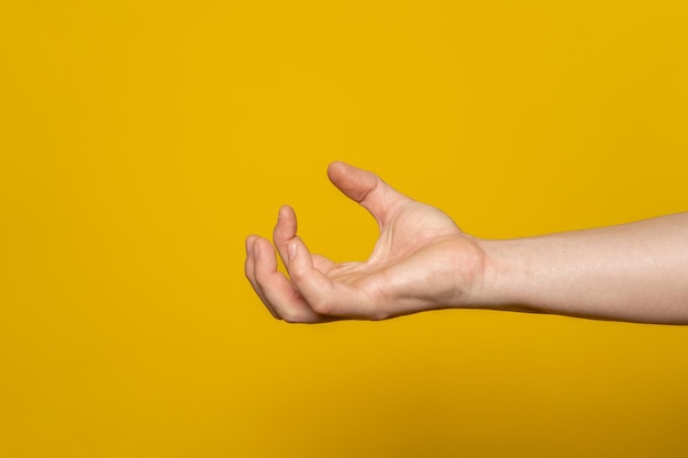 Mano recortada haciendo gestos contra un fondo amarillo