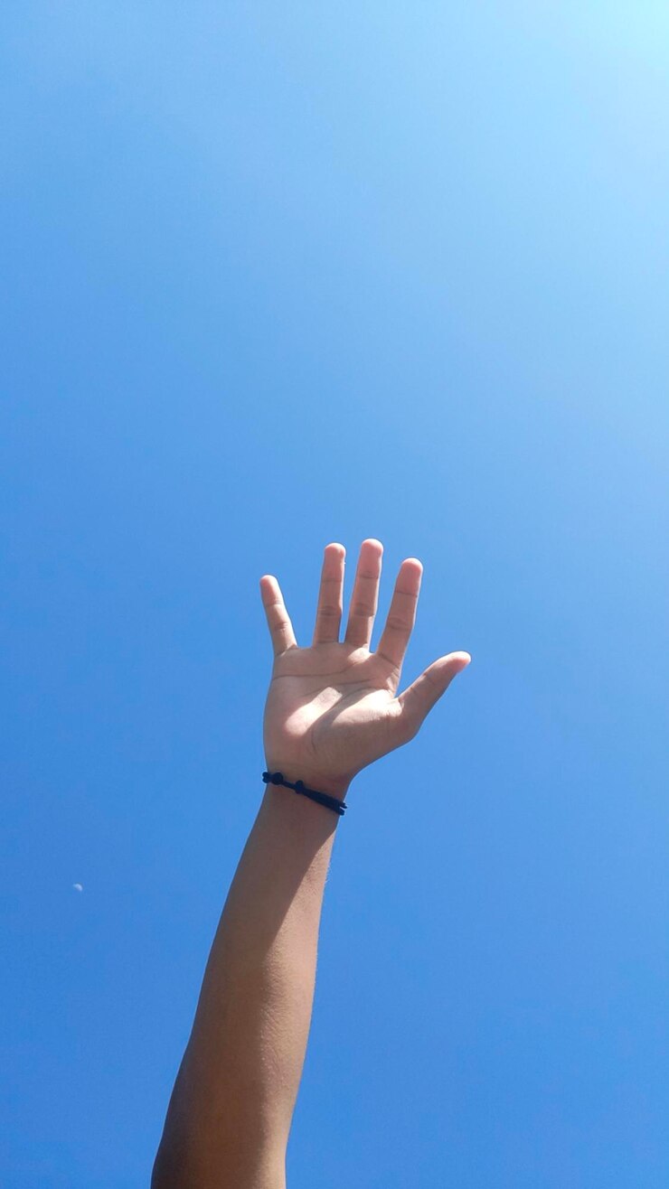 Foto mano recortada haciendo gestos contra un fondo azul