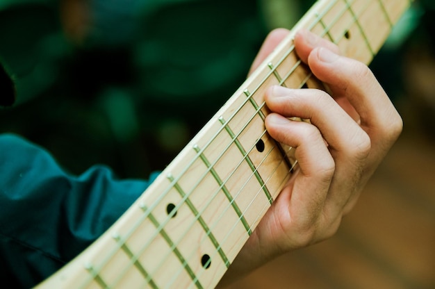 Foto mano recortada de un hombre tocando un instrumento de cuerda