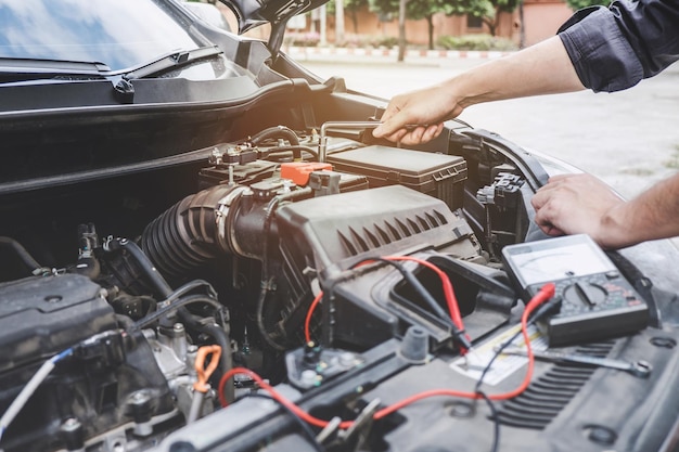 Foto mano recortada de un mecánico reparando el motor de un automóvil al aire libre