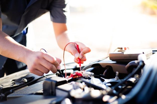 Mano recortada de un mecánico reparando el motor de un automóvil en un taller