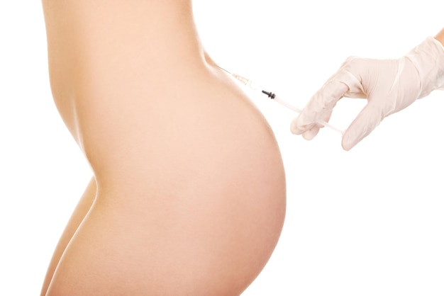 Mano recortada de un médico inyectando una jeringa en la espalda de una mujer contra un fondo blanco