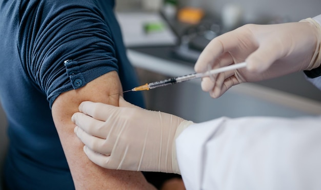 Mano recortada del médico que inyecta la jeringa en el brazo del paciente