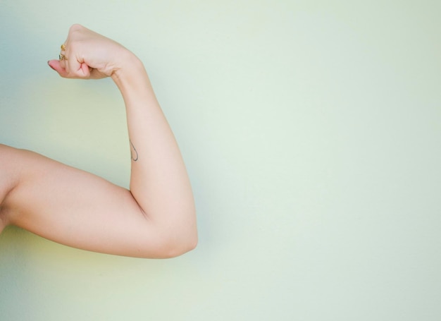 Mano recortada de una mujer flexionando el músculo contra un fondo blanco