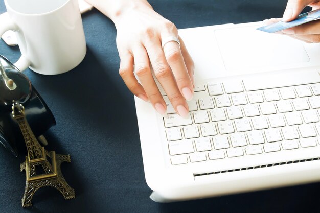 Foto mano recortada de una mujer sosteniendo una tarjeta de crédito mientras escribe en el teclado de la computadora