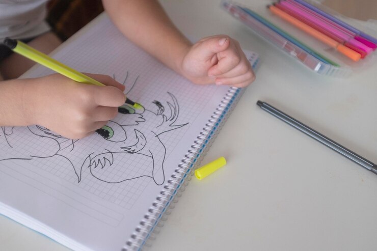 Foto mano recortada de un niño dibujando en un libro