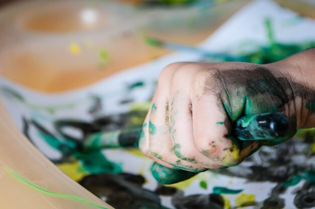 Foto mano recortada de un niño sosteniendo un pincel en el papel