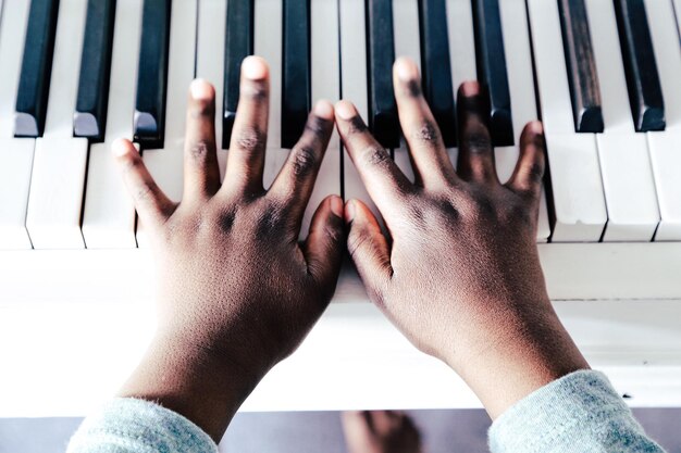 Mano recortada de un niño tocando el piano