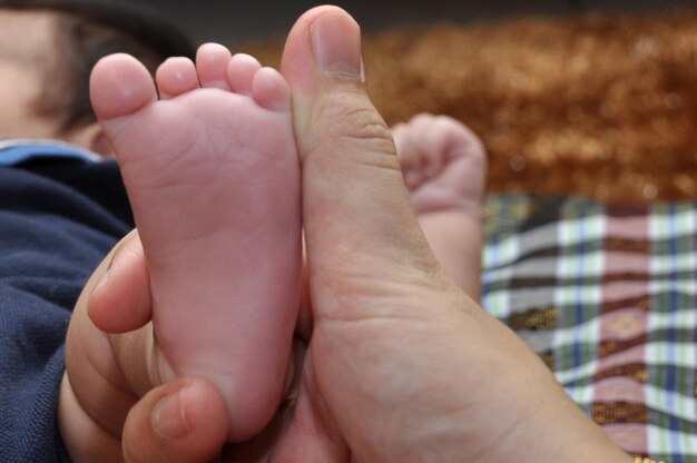 Mano recortada del padre sosteniendo el pie del bebé