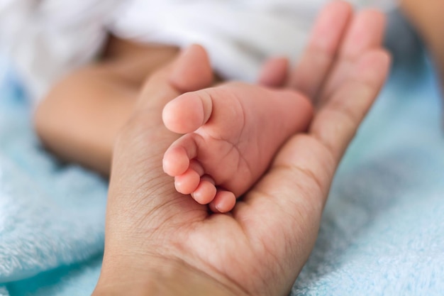 Foto mano recortada del padre sosteniendo el pie del bebé