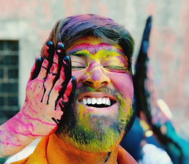 Foto mano recortada de una persona aplicando pintura en polvo en la cara de un hombre sonriente