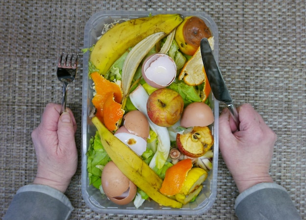 Mano recortada de una persona con cáscara de comida en la mesa
