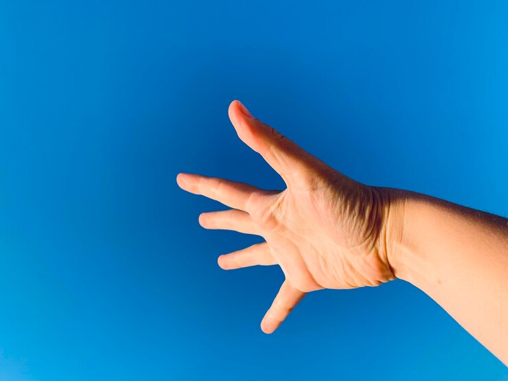 Foto mano recortada de una persona contra el cielo azul