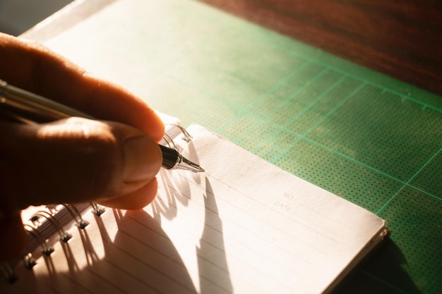 Foto mano recortada de una persona escribiendo en un bloc de notas