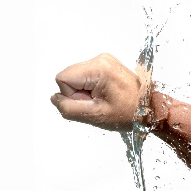 Foto mano recortada de una persona golpeando agua contra un fondo blanco