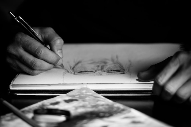 Mano recortada de una persona que dibuja en papel