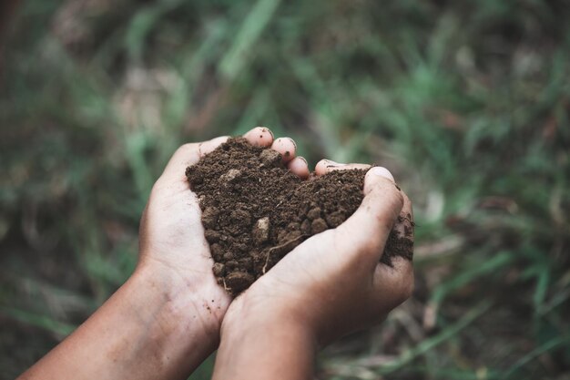 Foto mano recortada de una persona que sostiene barro en forma de corazón