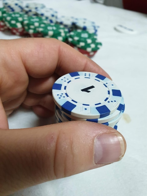 Foto mano recortada de una persona que sostiene fichas de juego en la mesa