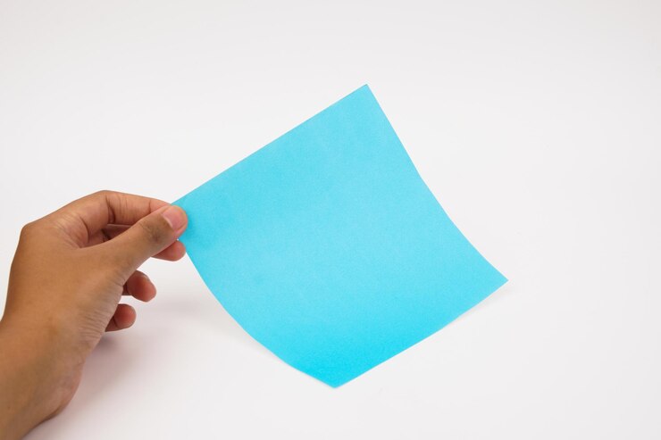 Foto mano recortada de una persona que sostiene un papel en blanco contra un fondo blanco