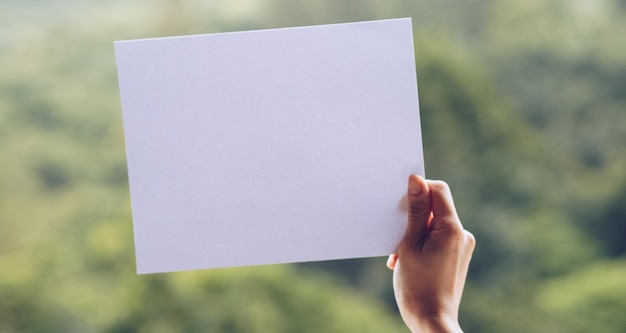Mano recortada de una persona que sostiene un papel en blanco