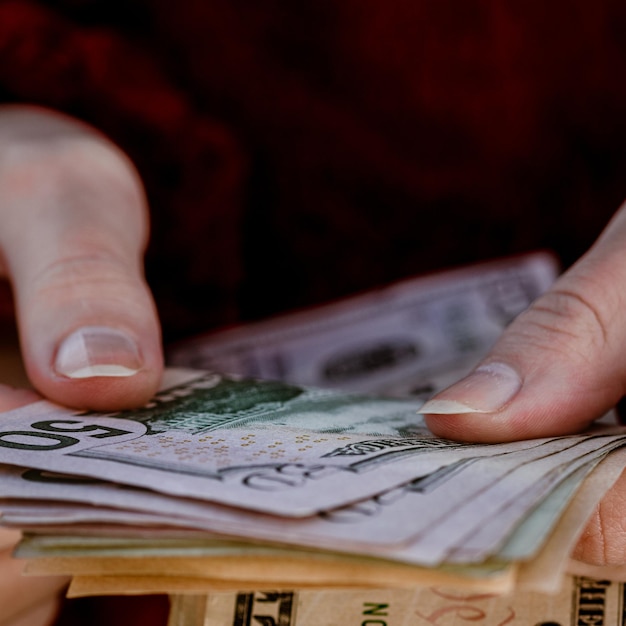Mano recortada de una persona que sostiene papel moneda
