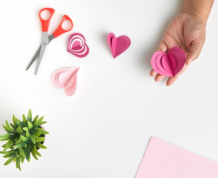 Foto mano recortada sosteniendo artesanía de papel en forma de corazón sobre fondo blanco