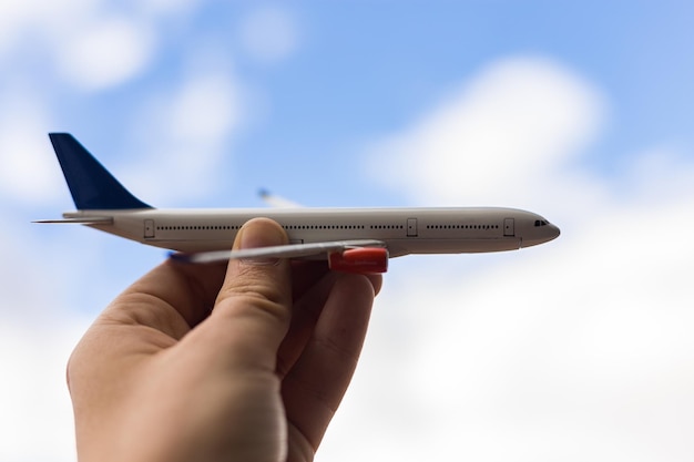 Mano recortada sosteniendo un avión de juguete contra el cielo