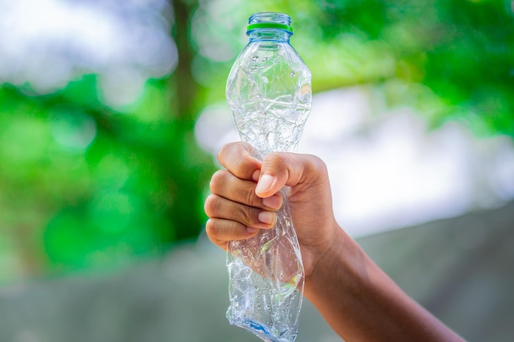 Foto mano recortada sosteniendo una botella de agua vacía