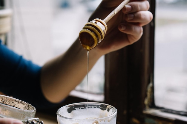 La mano recortada sosteniendo el dipper de la miel