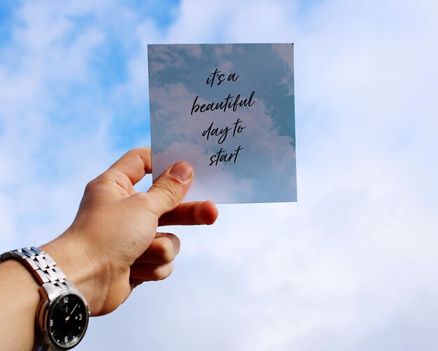 Foto mano recortada sosteniendo papel con texto contra el cielo