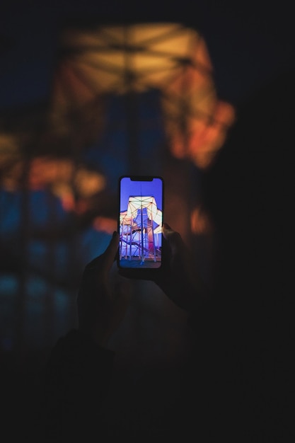 Mano recortada sosteniendo un teléfono móvil por la noche