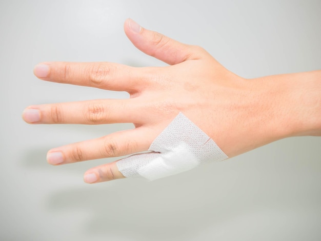 Mano recortada con vendaje contra un fondo blanco