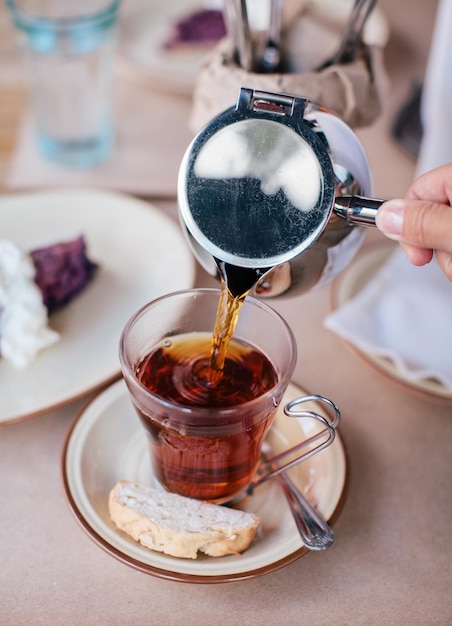 Mano recortada vertiendo bebida en una taza en la mesa