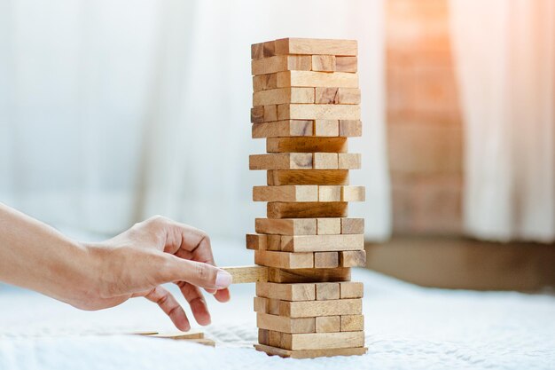 Mano sacando o colocando bloques de madera en la torre en la oficina moderna. plan y estrategia en los negocios. desenfoque de fondo.