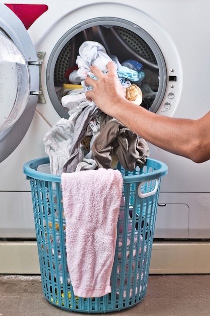 Foto mano sacando la ropa de la lavadora a la cesta.