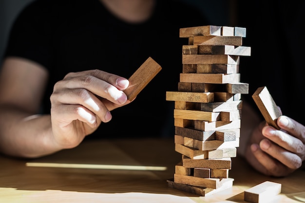 mano sacar bloque de pieza de madera de estrategia de pila y concepto de riesgo