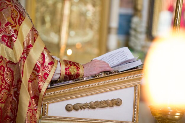 Mano del sacerdote en el escritorio leyendo la Biblia en la iglesia ortodoxa horizontal