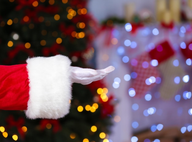 Mano de Santa Claus contra las luces de Navidad borrosas